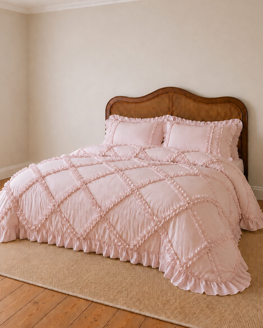 Pink quilted bedspread on a wooden bed with a wooden headboard in a room with beige walls and wooden flooring.