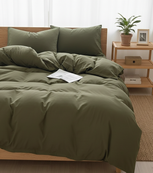 Green bedding set on a bed in a bedroom with a wooden nightstand and plant.